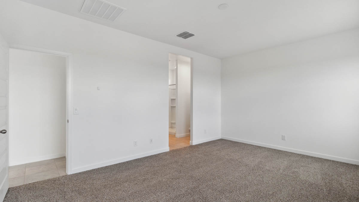 A spacious primary bedroom emphasizing open space and natural lighting.