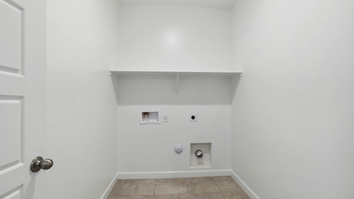 Spacious laundry room with washer and dryer connections and shelving for storage.
