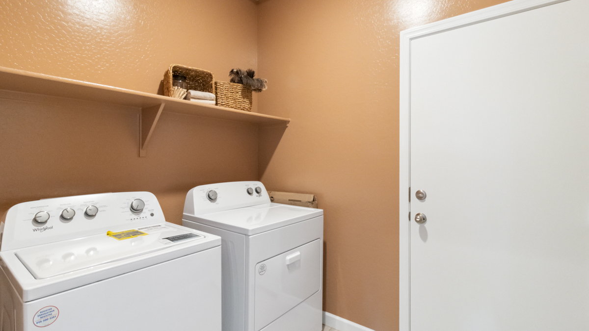 A laundry room featuring a washer and dryer, neatly arranged with ample space for laundry tasks and storage.