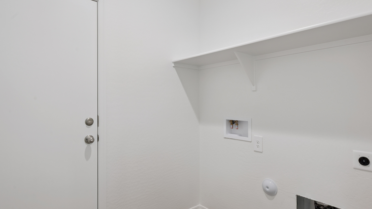 Spacious laundry room with washer and dryer connections and shelving for storage.
