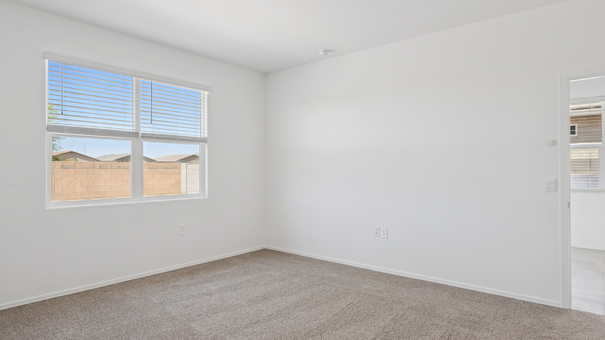 A spacious primary bedroom emphasizing open space and natural lighting.