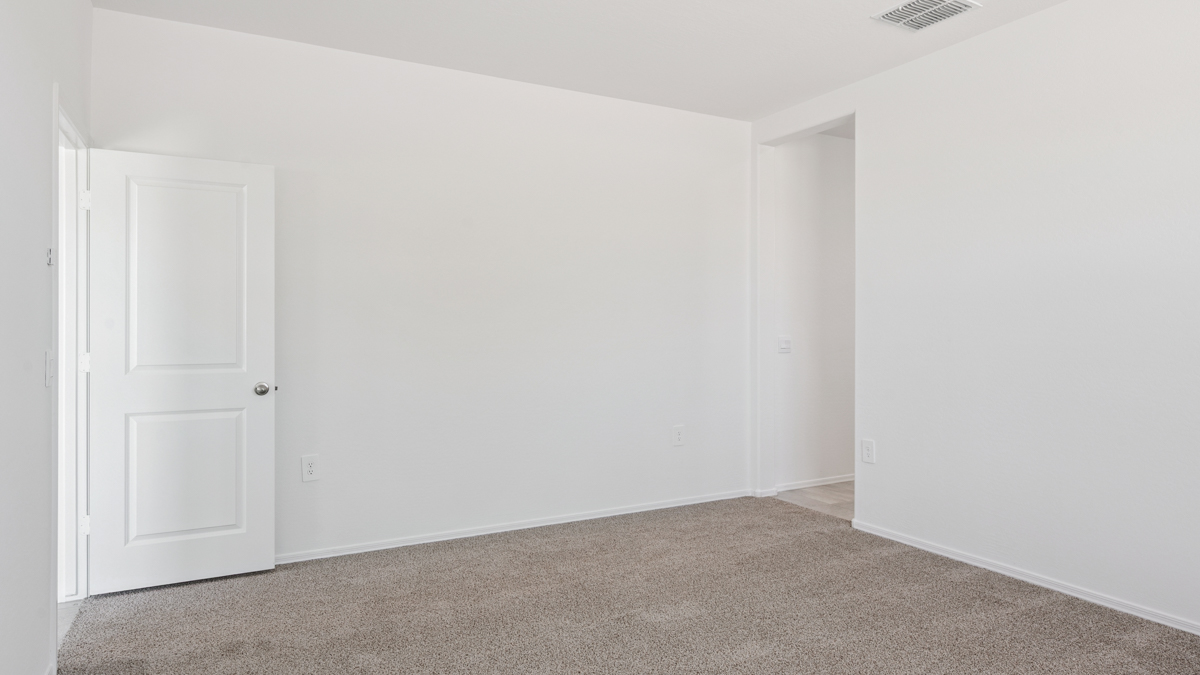 A spacious primary bedroom emphasizing open space and natural lighting.