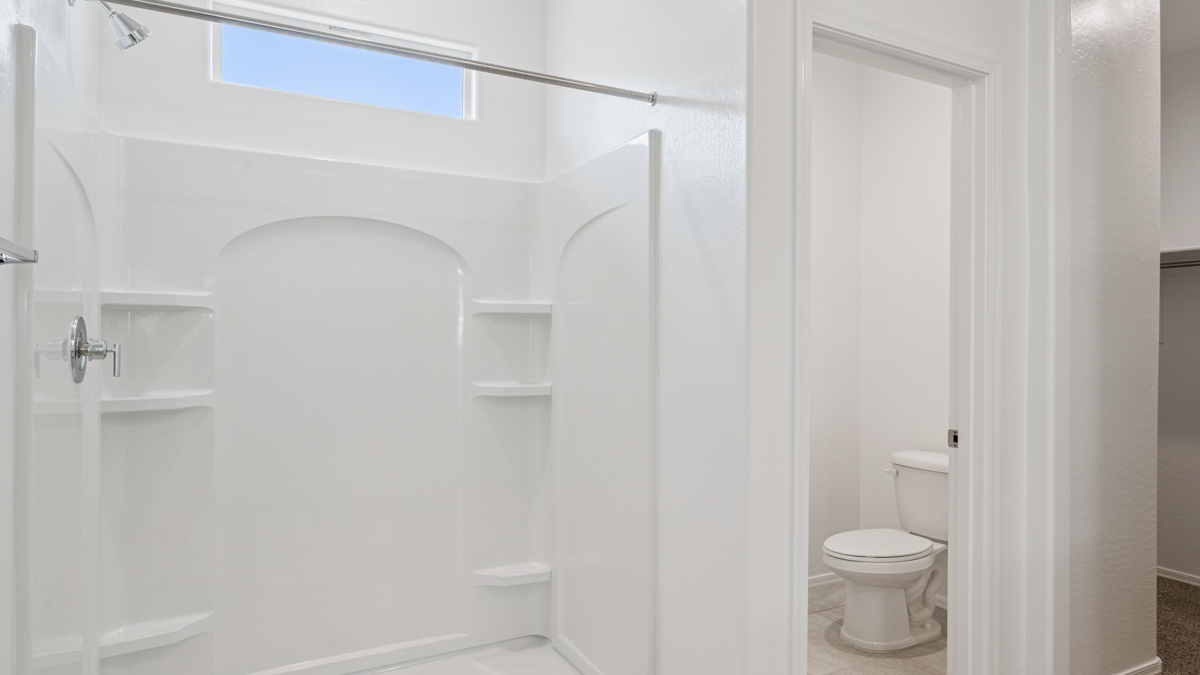 Modern primary bathroom with double vanity, granite countertops with a walk-in shower and a walk-in closet.