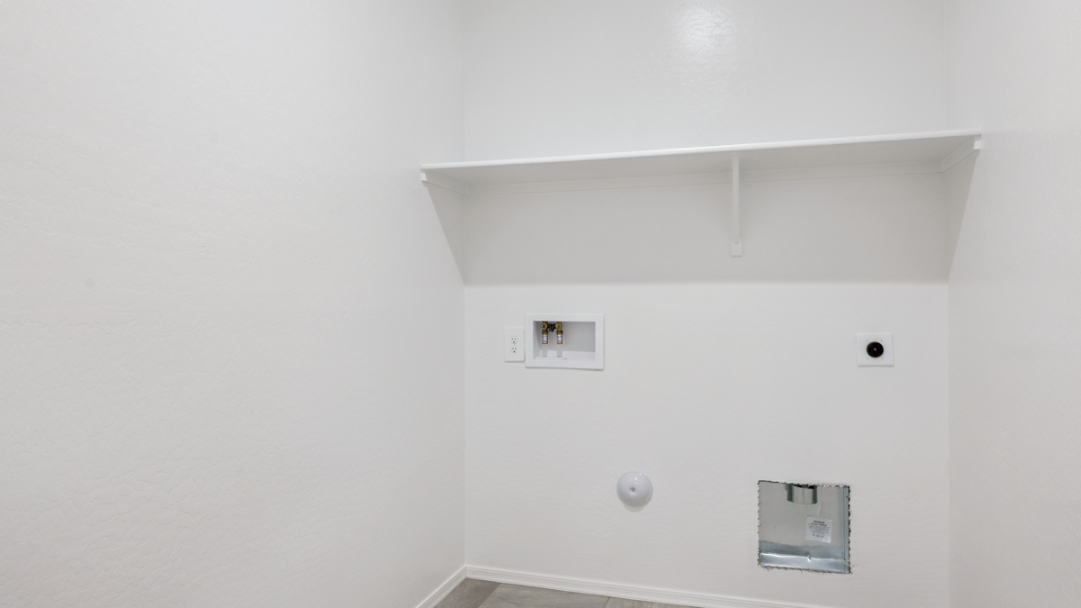 Spacious laundry room with washer and dryer connections and shelving for storage.