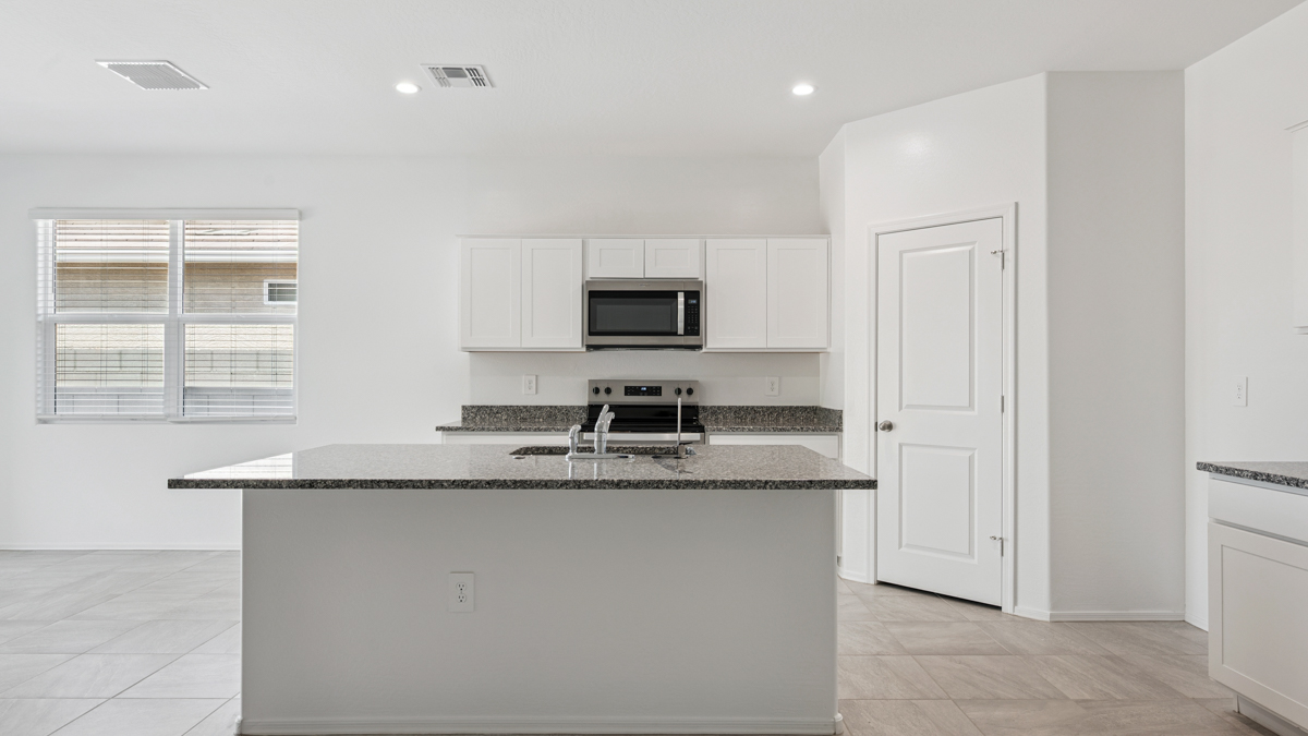 Bright and spacious kitchen with granite countertops, stainless steel appliances, and an island with bar seating.