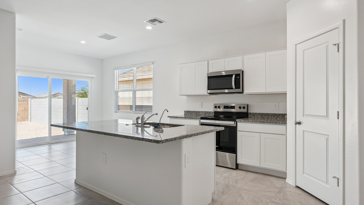 Bright and spacious kitchen with granite countertops, stainless steel appliances, and an island with bar seating.