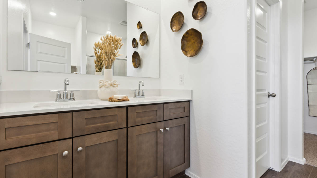 Modern primary bathroom with double vanities, quartz countertops with a walk-in shower and a walk-in closet.