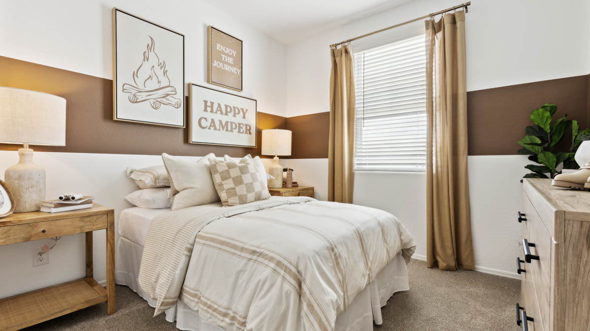 A vibrant kids' bedroom showcasing a neatly made bed, a stylish dresser, and a playful painting that adds charm.