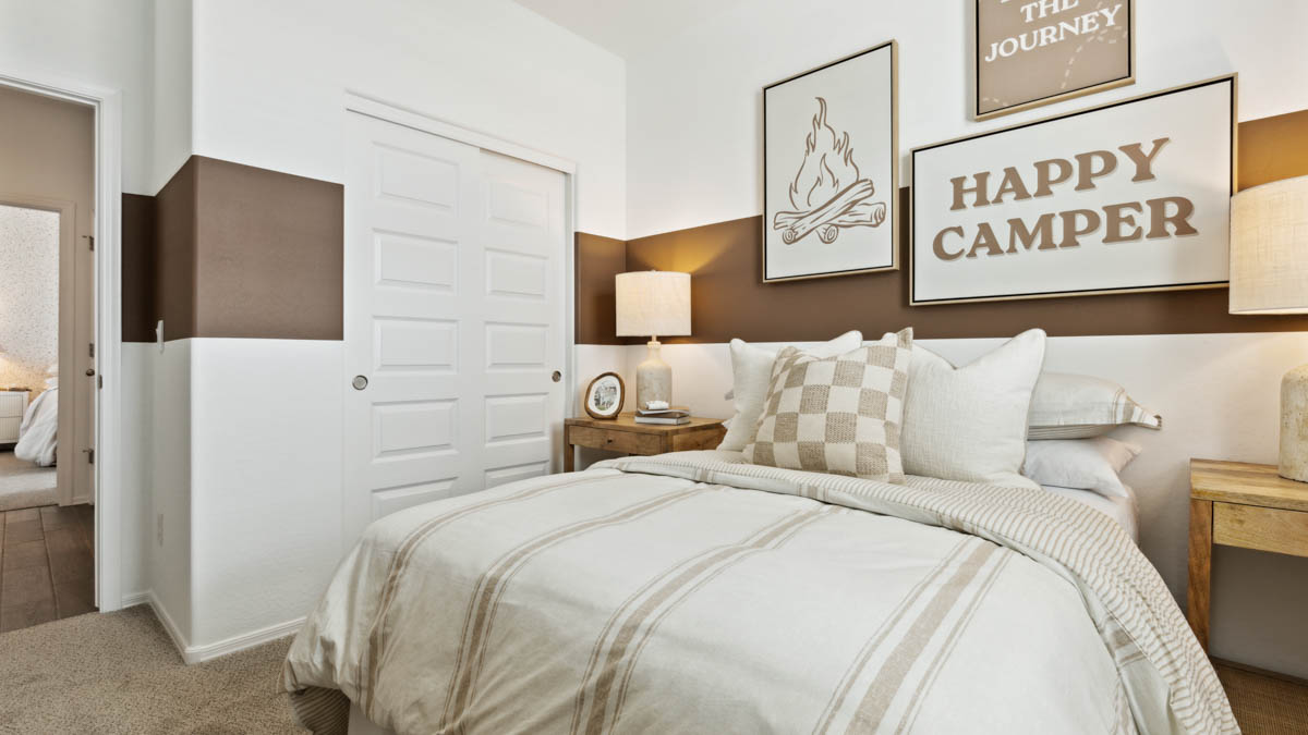 A vibrant kids' bedroom showcasing a neatly made bed, a stylish dresser, and a playful painting that adds charm.