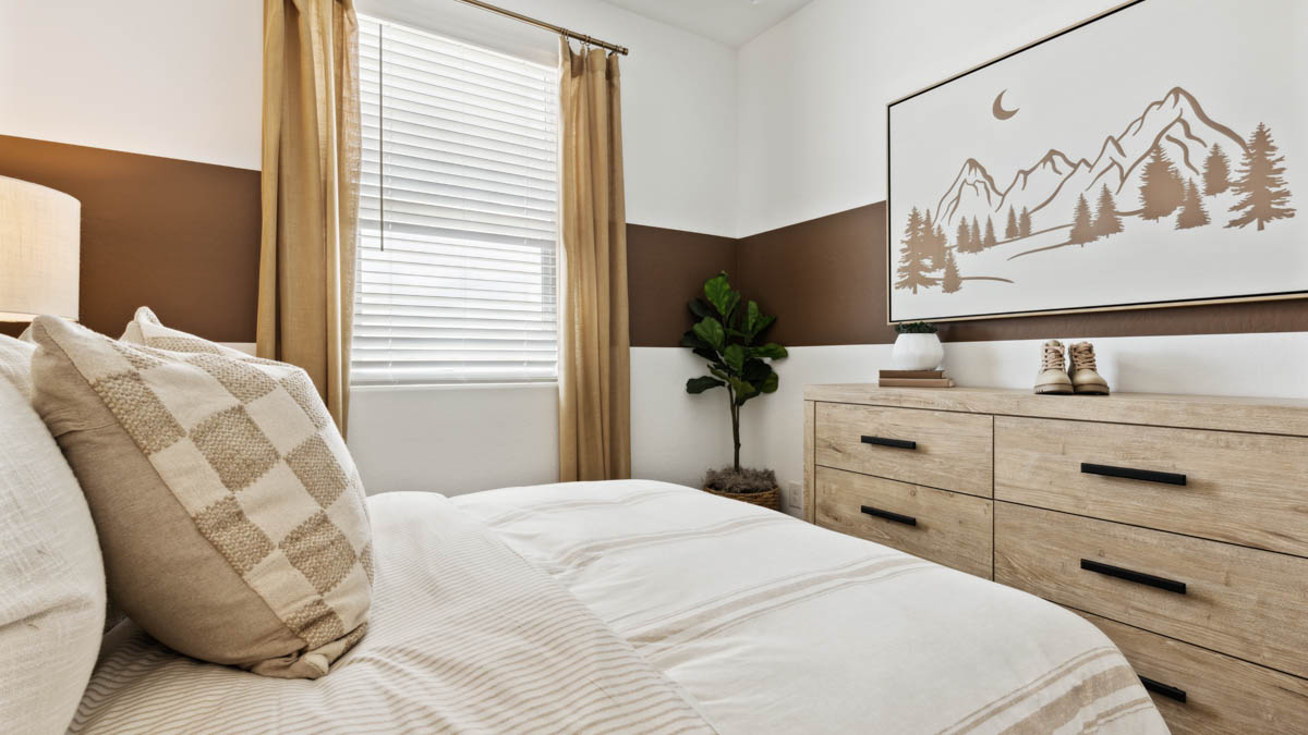 A vibrant kids' bedroom showcasing a neatly made bed, a stylish dresser, and a playful painting that adds charm.