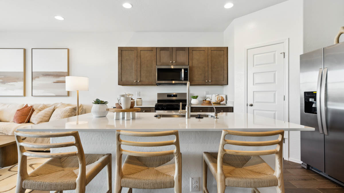 Bright and spacious kitchen with quartz countertops, stainless steel appliances, and an island with bar seating.