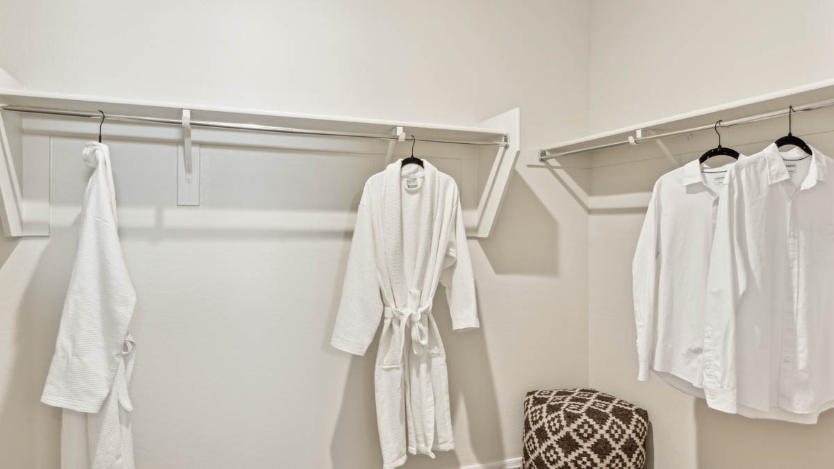 Modern primary bathroom with double vanity, granite countertops with a walk-in shower and a walk-in closet.
