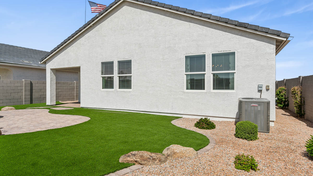 Outdoor covered patio with seating area overlooking a well-maintained lawn, perfect for relaxation.