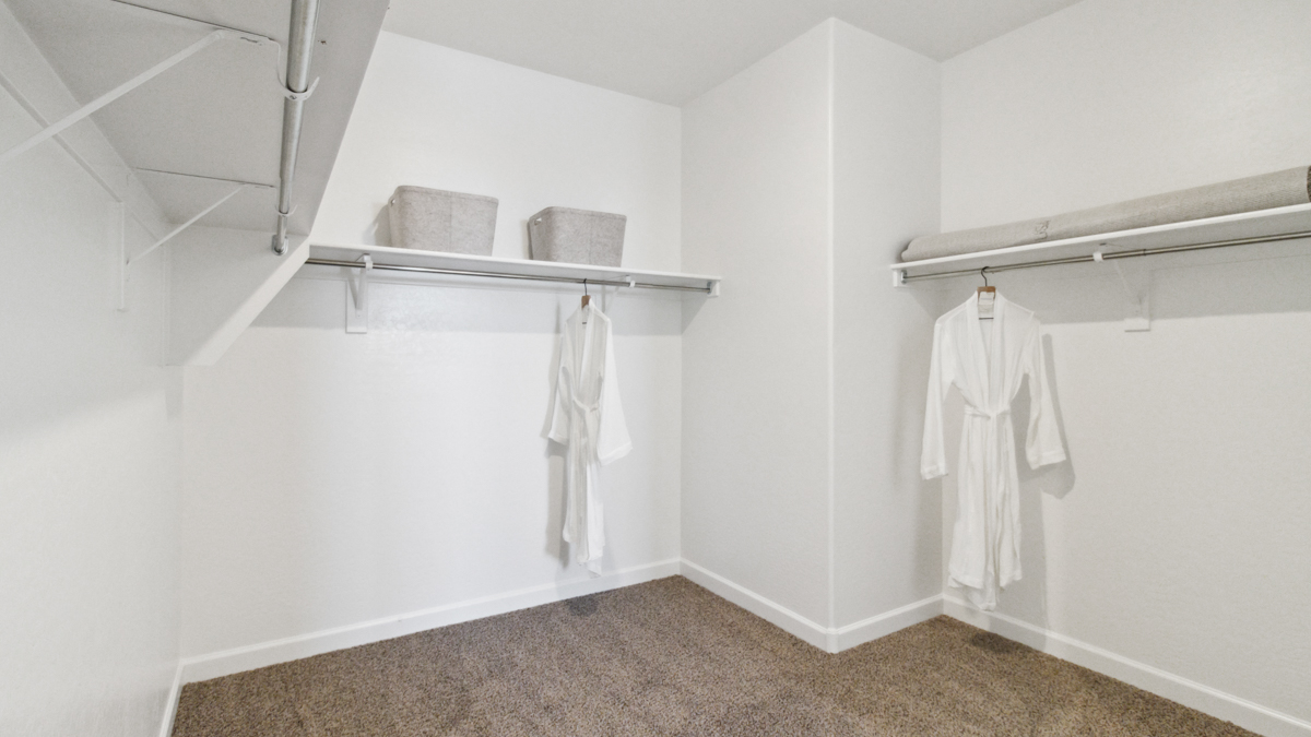Modern primary bathroom with double vanity, granite countertops with a walk-in shower and a walk-in closet.