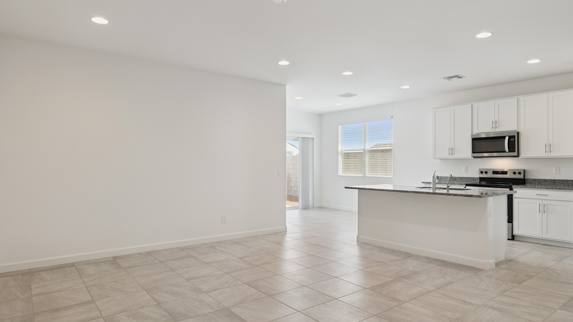 Bright and spacious kitchen with granite countertops, stainless steel appliances, and an island with bar seating.