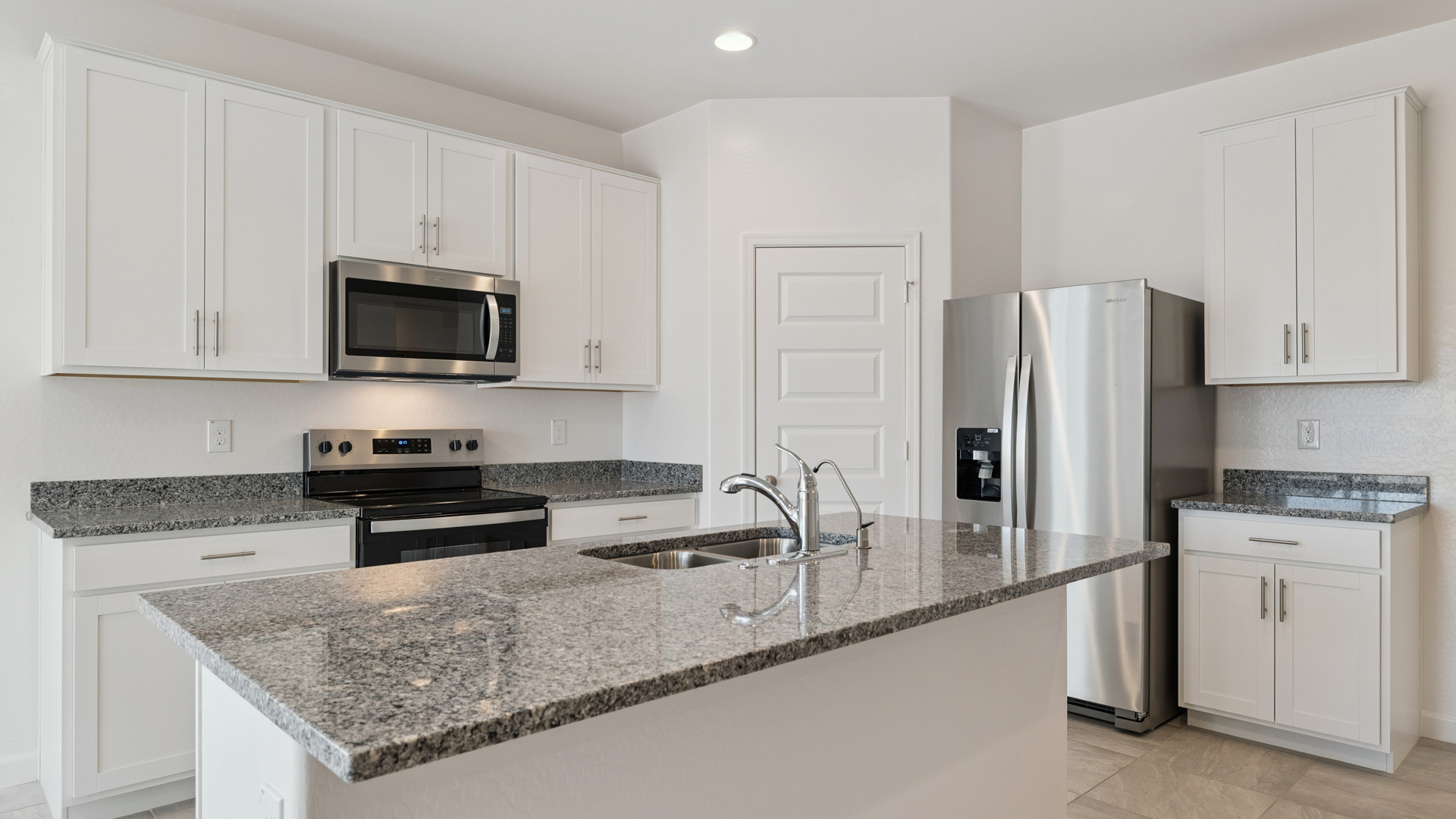 Bright and spacious kitchen with granite countertops, stainless steel appliances, and an island with bar seating.