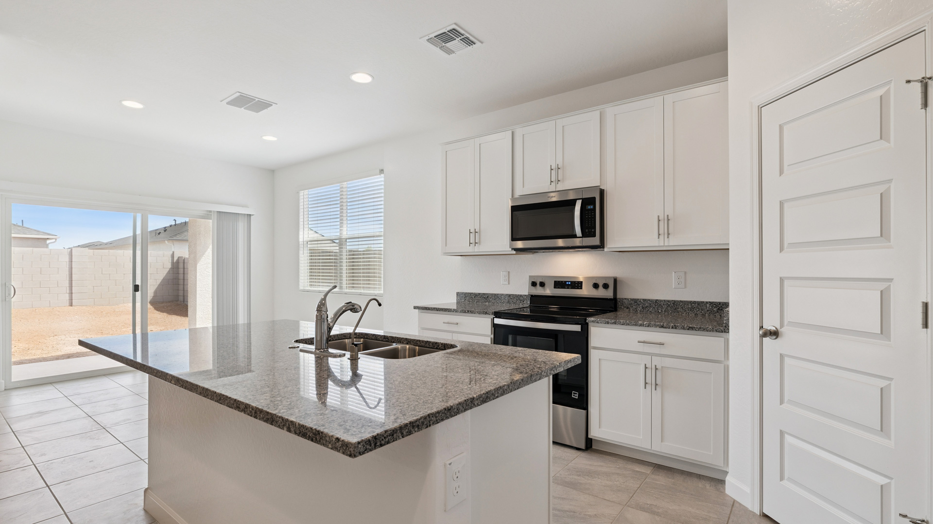 Bright and spacious kitchen with granite countertops, stainless steel appliances, and an island with bar seating.