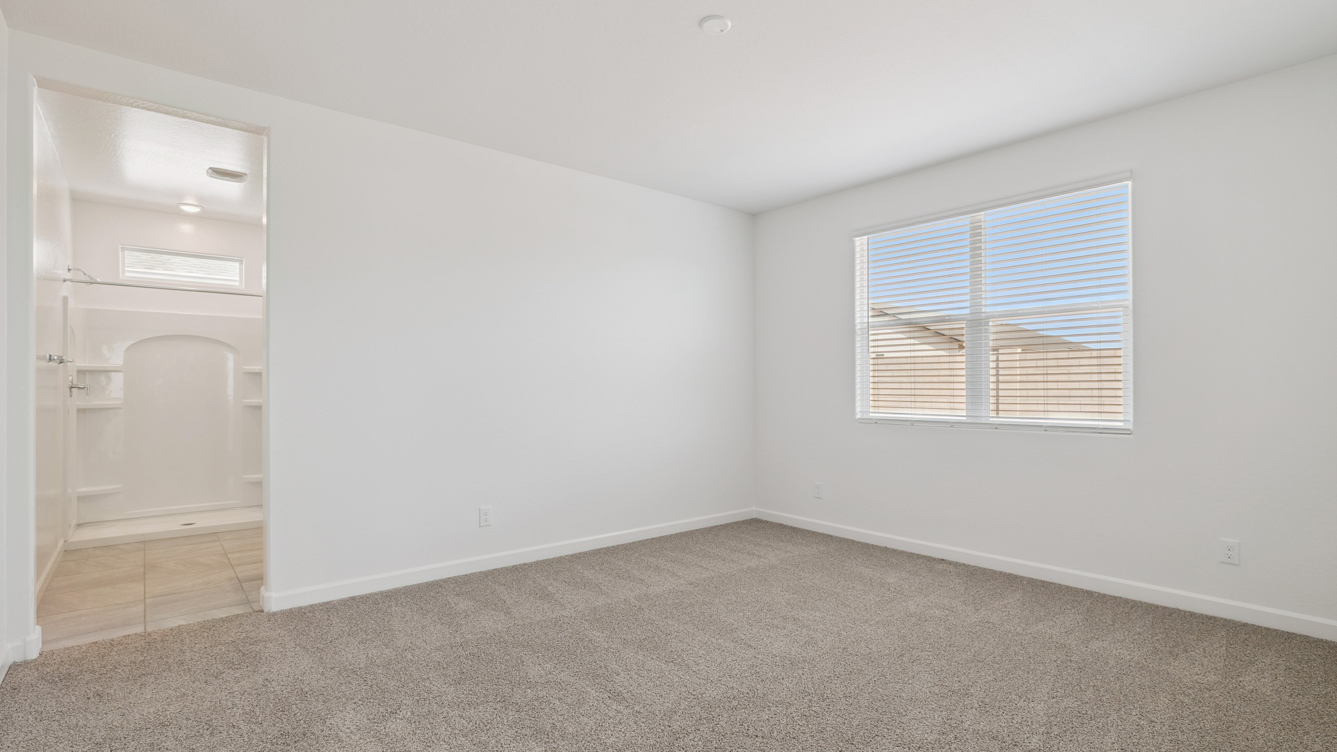 A spacious primary bedroom emphasizing open space and natural lighting.