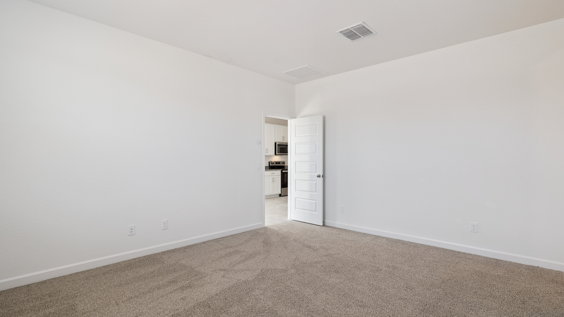 A spacious primary bedroom emphasizing open space and natural lighting.