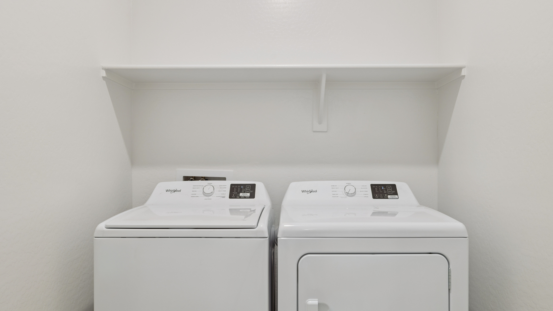 Spacious laundry room with washer and dryer connections and shelving for storage.
