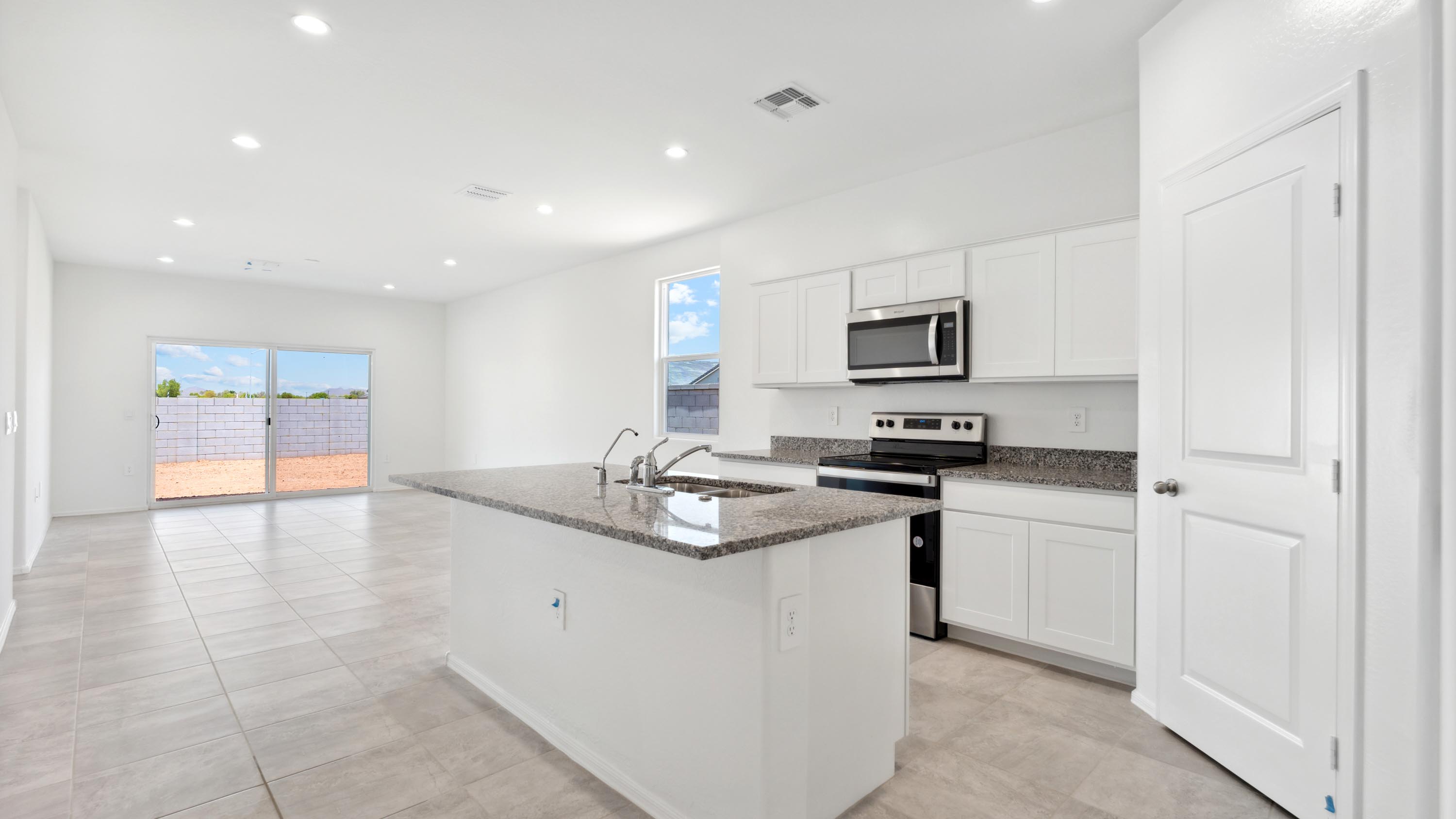 Bright and spacious kitchen with granite countertops, stainless steel appliances, and an island with bar seating.