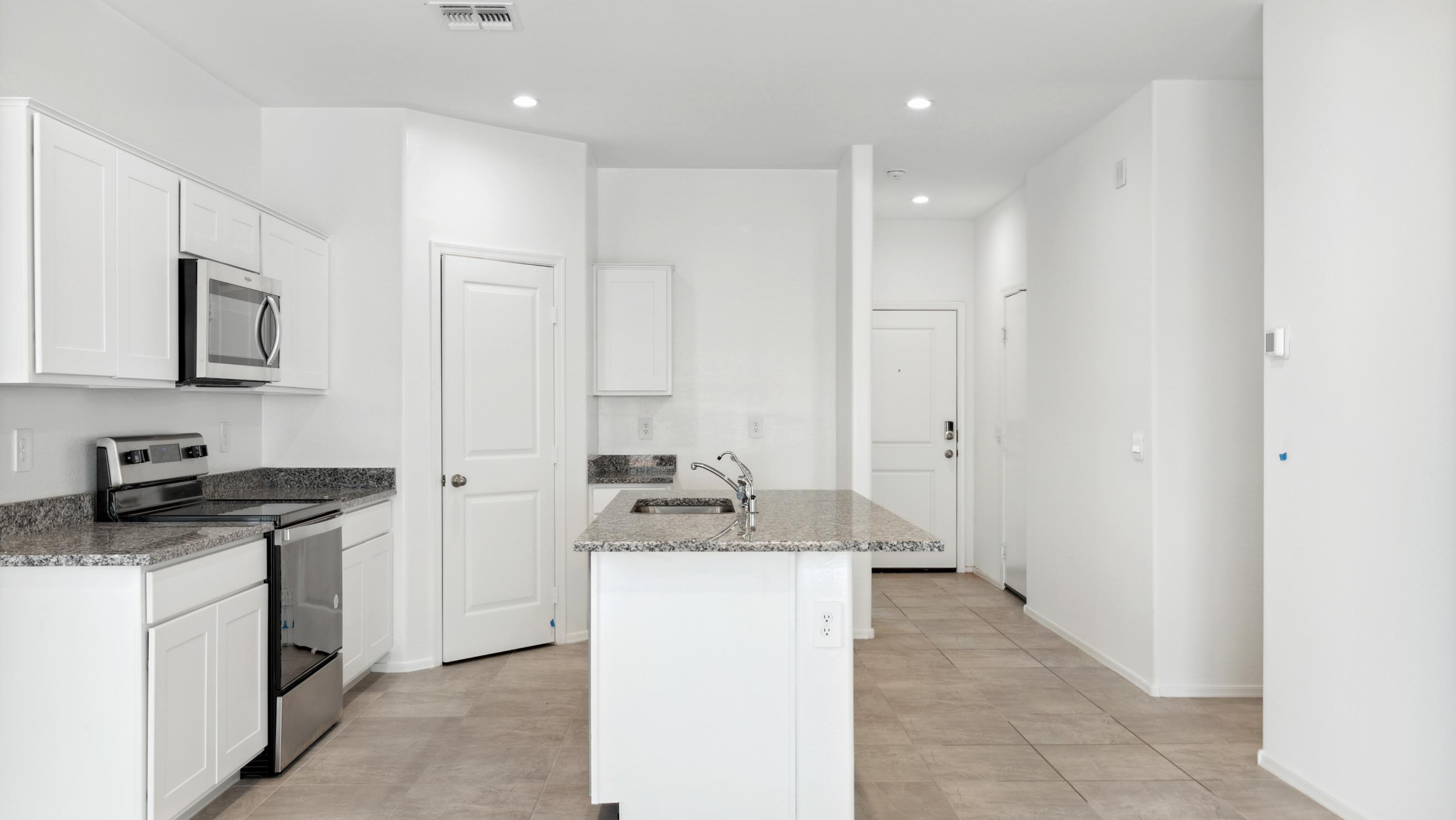 Bright and spacious kitchen with granite countertops, stainless steel appliances, and an island with bar seating.