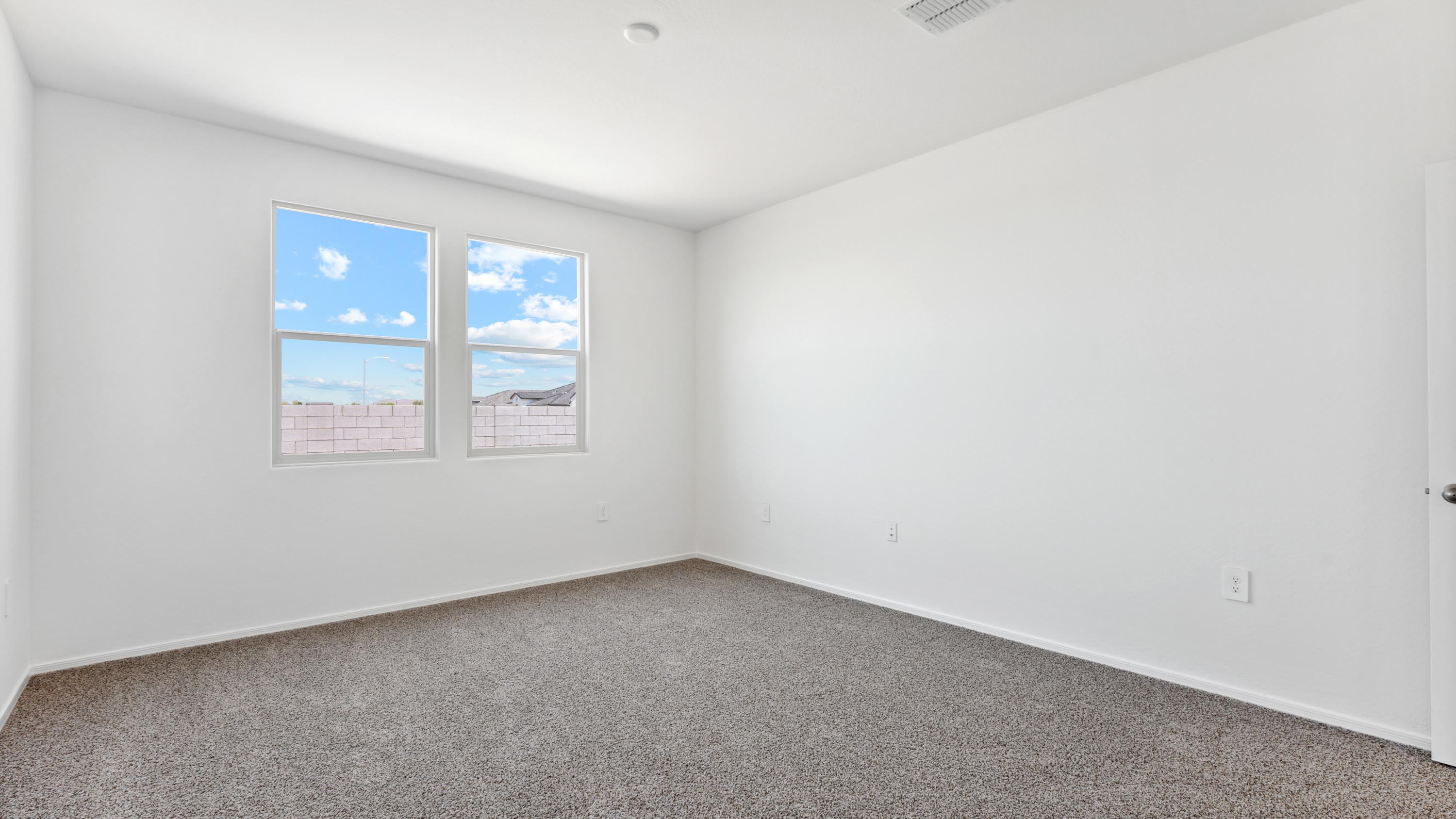 A spacious primary bedroom emphasizing open space and natural lighting.