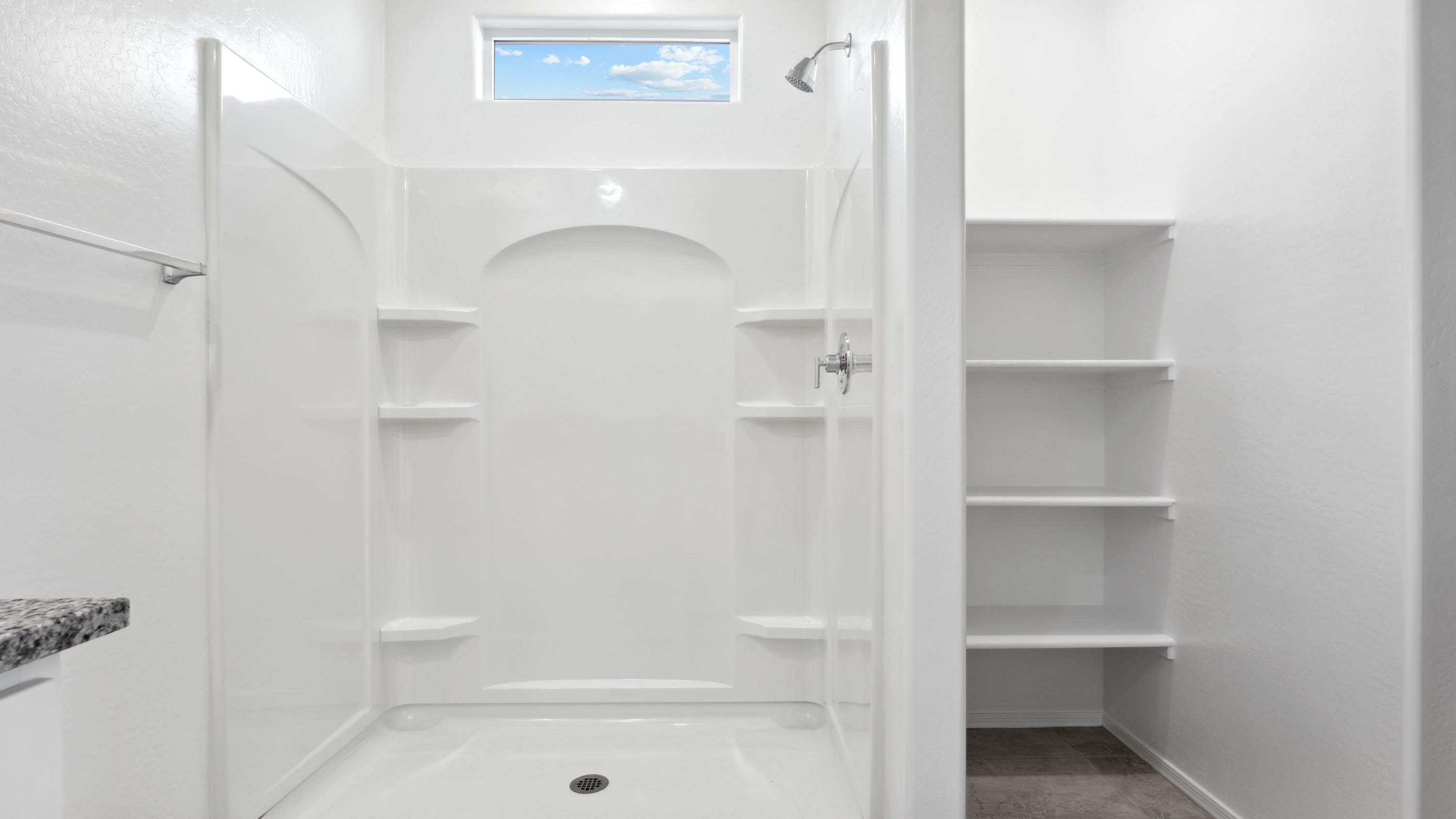 Modern primary bathroom with double vanity, granite countertops with a walk-in shower and a walk-in closet.