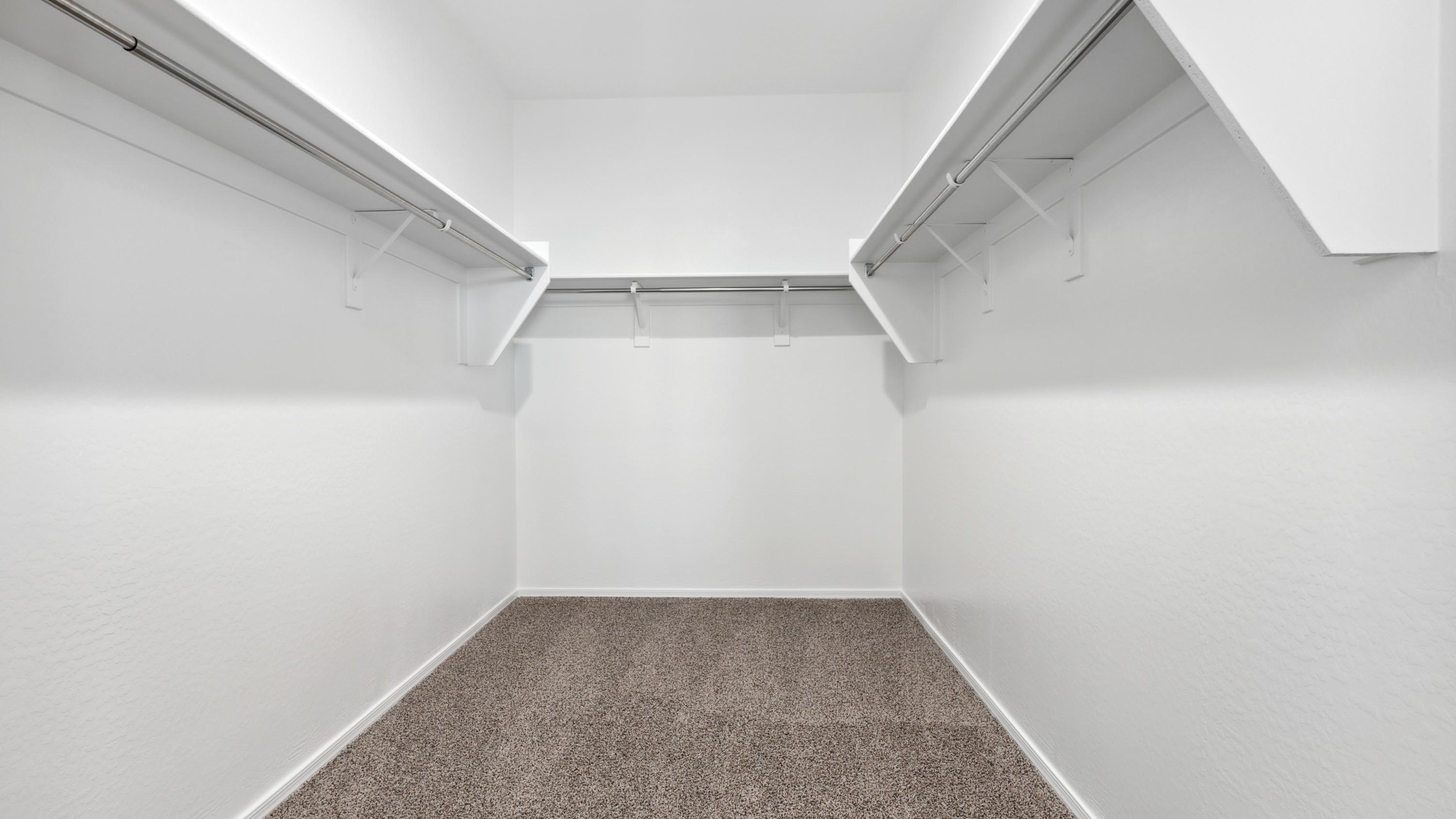 Modern primary bathroom with double vanity, granite countertops with a walk-in shower and a walk-in closet.