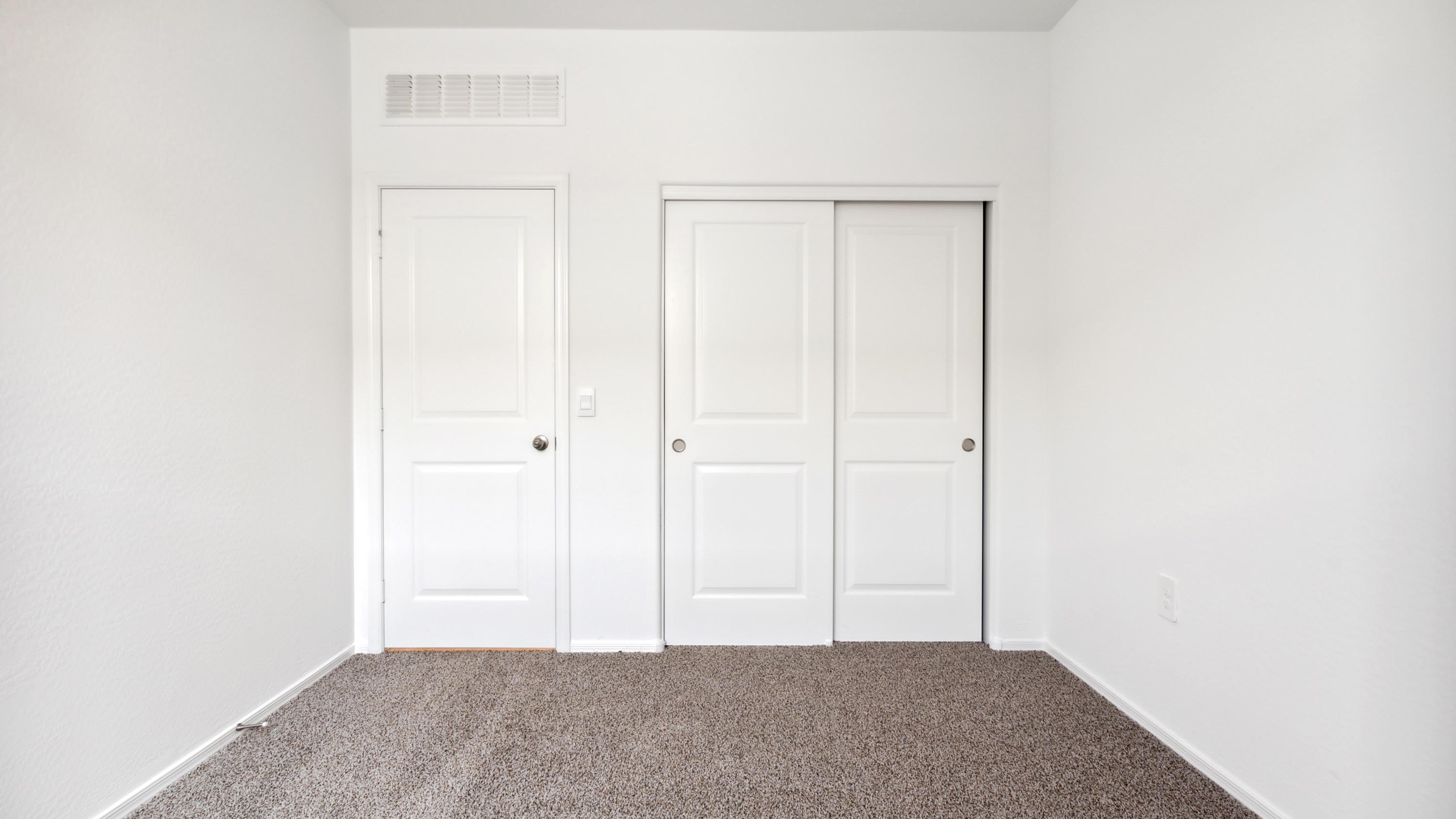Comfortable guest bedroom featuring neutral-toned walls and a large closet.