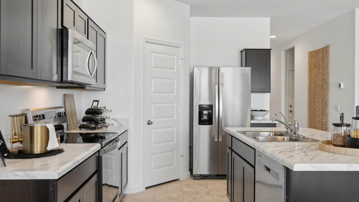 Bright and spacious kitchen with porcelain countertops, stainless steel appliances, and an island with bar seating.