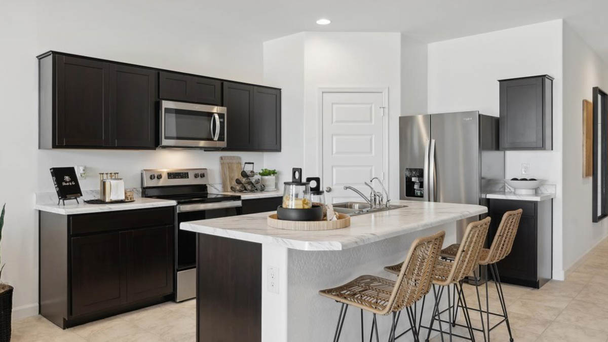 Bright and spacious kitchen with porcelain countertops, stainless steel appliances, and an island with bar seating.