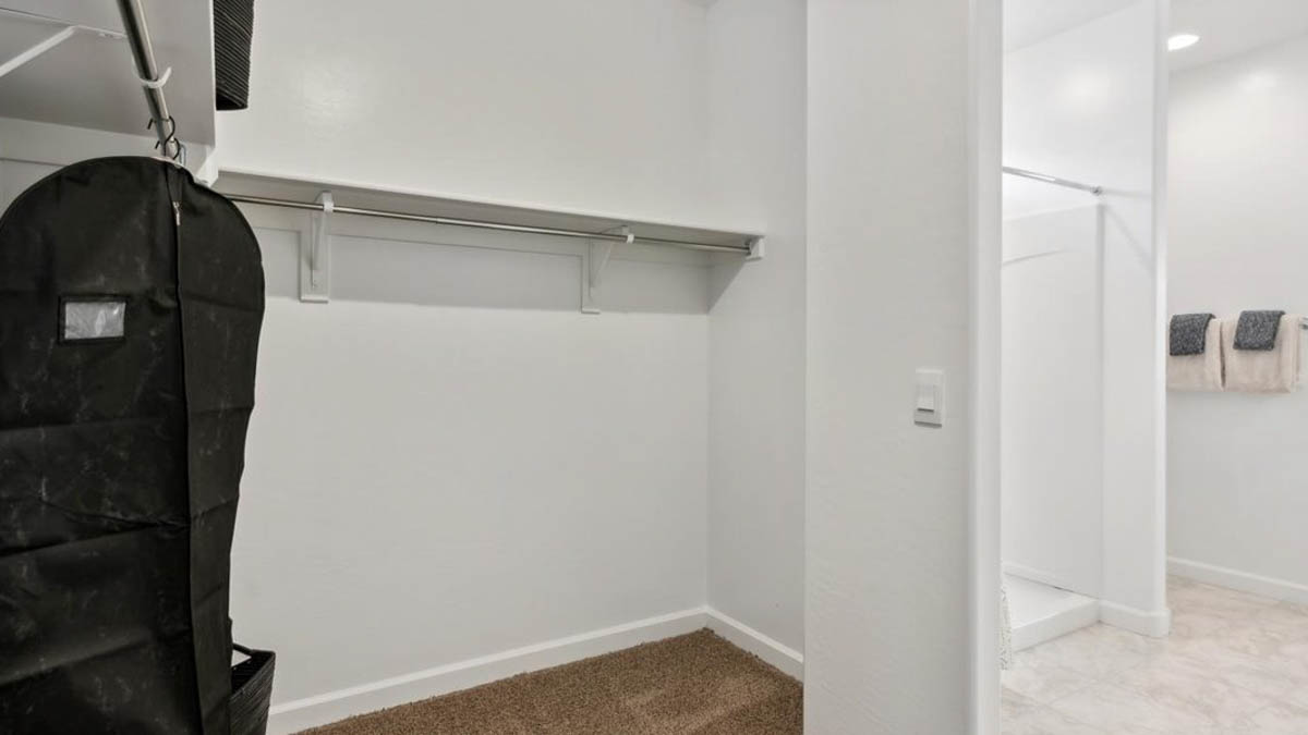Modern primary bathroom with double vanities, porcelain countertops with a walk-in shower and a walk-in closet.