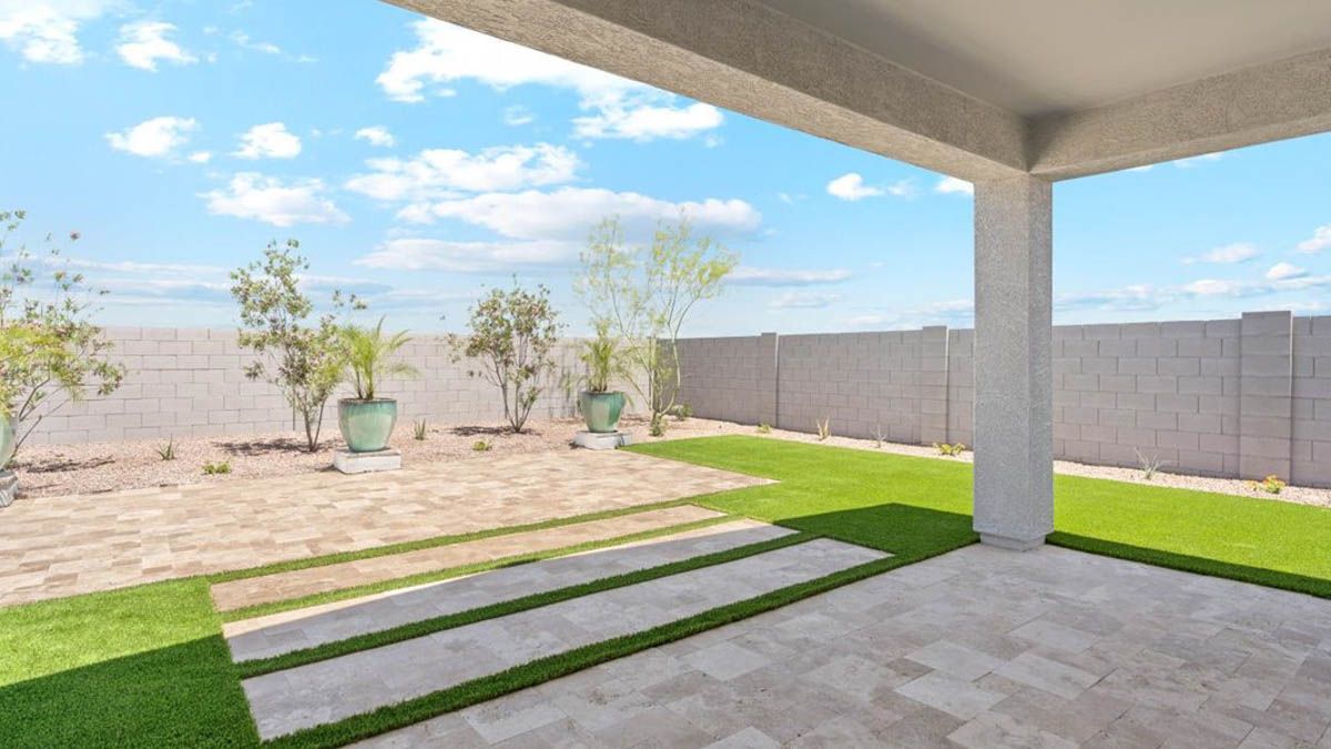 Outdoor covered patio with seating area overlooking a well-maintained lawn, perfect for relaxation.