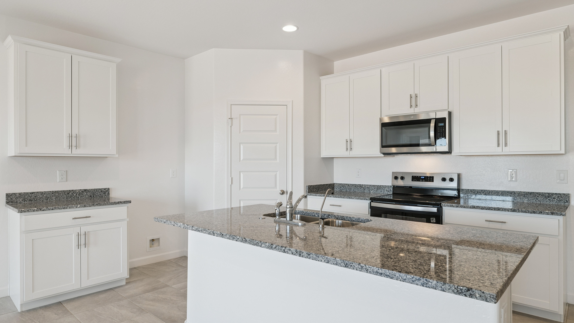 Bright and spacious kitchen with granite countertops, stainless steel appliances, and an island with bar seating.