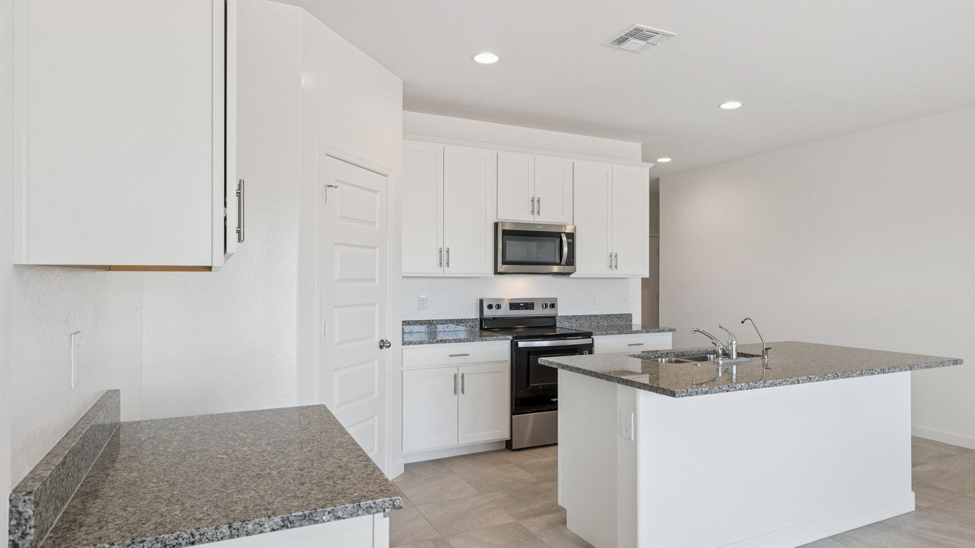 Bright and spacious kitchen with granite countertops, stainless steel appliances, and an island with bar seating.