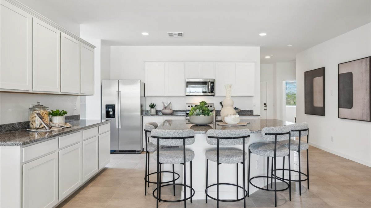 Bright and spacious kitchen with granite countertops, stainless steel appliances, and an island with bar seating.