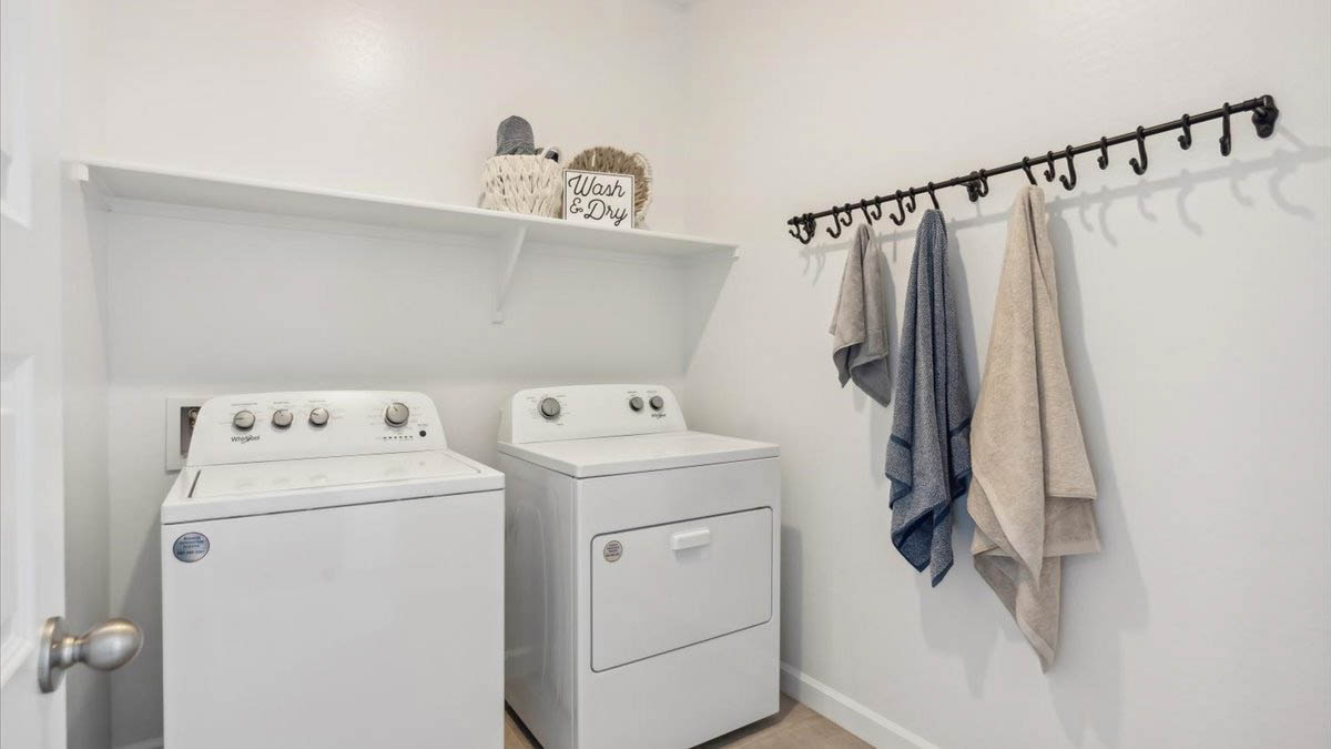 A laundry room featuring a washer and dryer, neatly arranged with ample space for laundry tasks and storage.