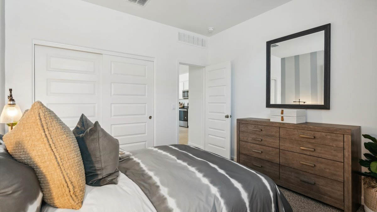 A vibrant kids' bedroom showcasing a neatly made bed, a stylish dresser, and a playful painting that adds charm.