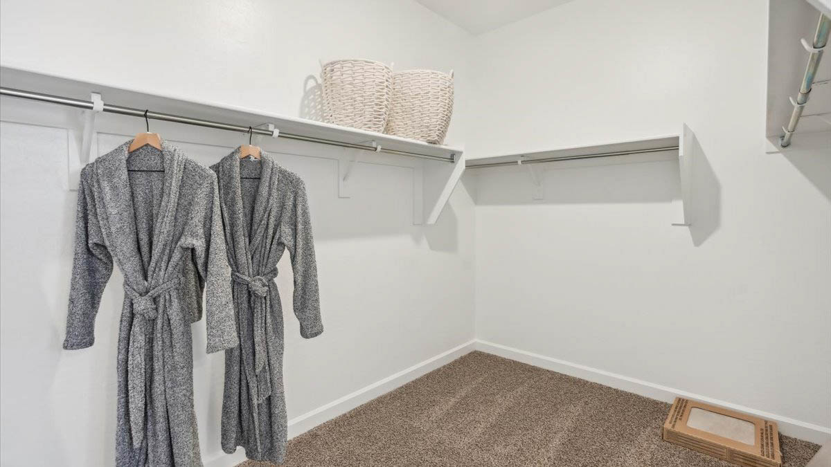 Modern primary bathroom with double vanity, granite countertops with a walk-in shower and a walk-in closet.