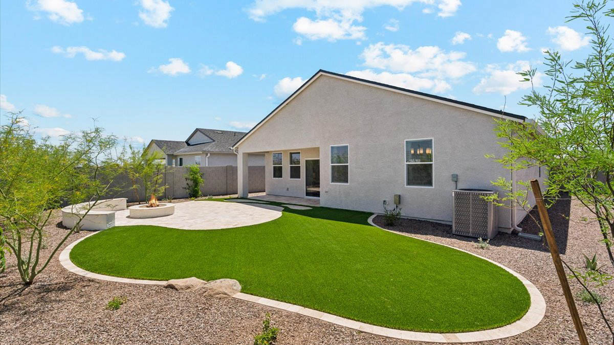 Outdoor covered patio with seating area overlooking a well-maintained lawn, perfect for relaxation.