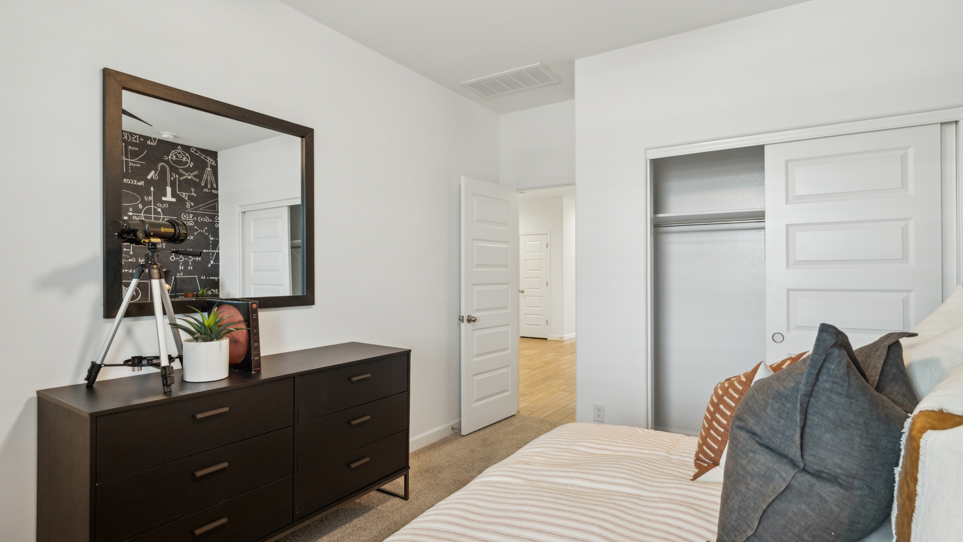 A vibrant kids' bedroom showcasing a neatly made bed, a stylish dresser, and a playful painting that adds charm.
