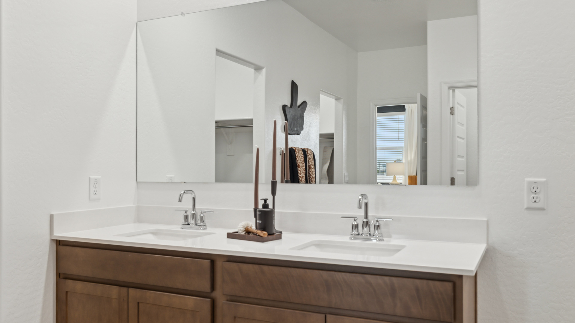 Modern primary bathroom with double vanities, quartz countertops with a walk-in shower and a walk-in closet.