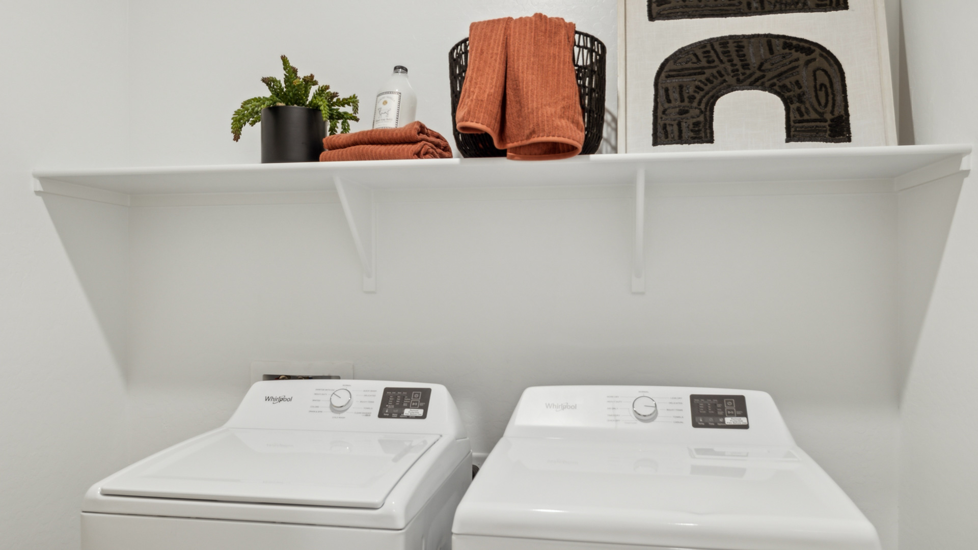 Spacious laundry room with washer and dryer connections and shelving for storage.