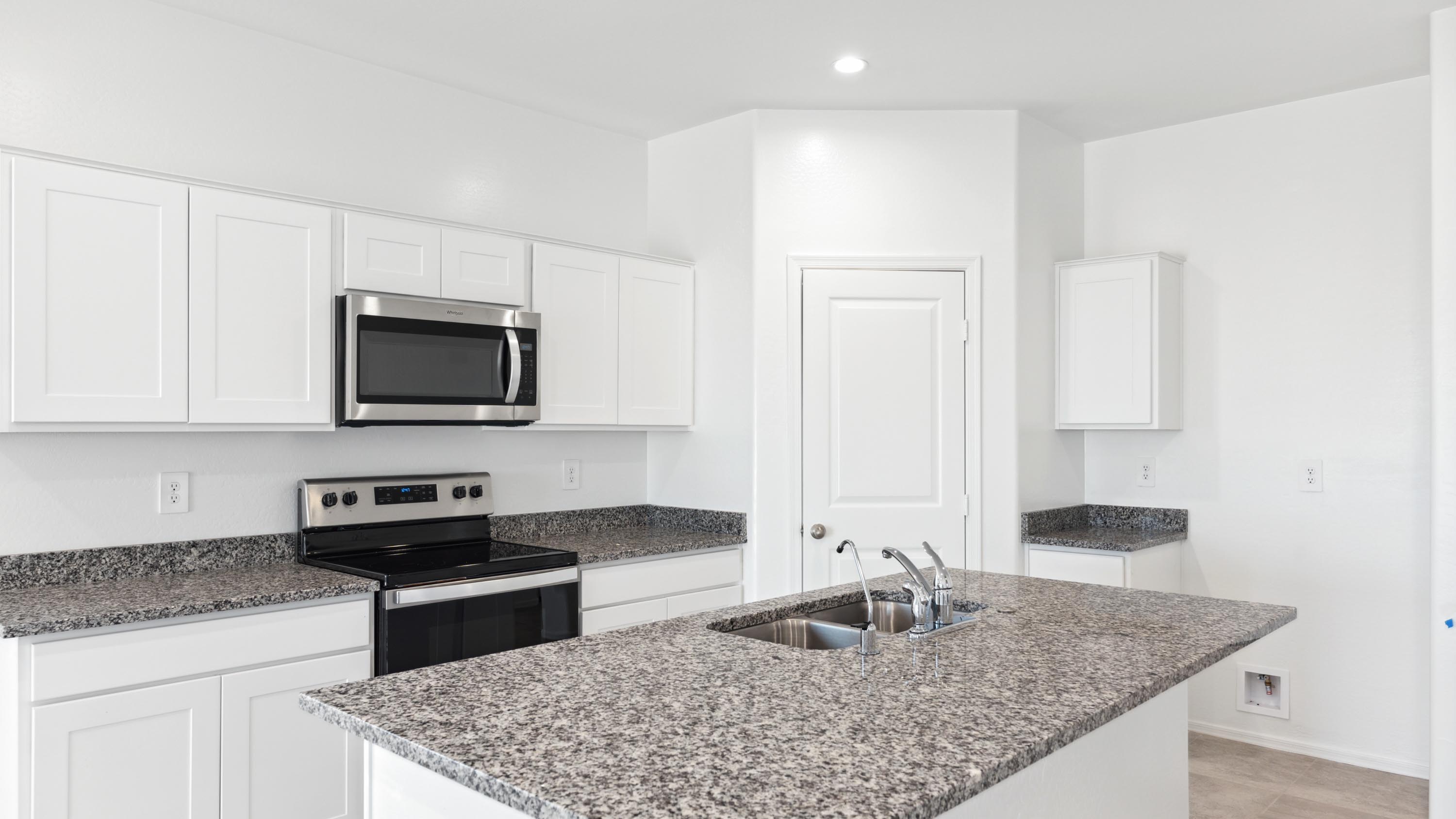 Bright and spacious kitchen with granite countertops, stainless steel appliances, and an island with bar seating.