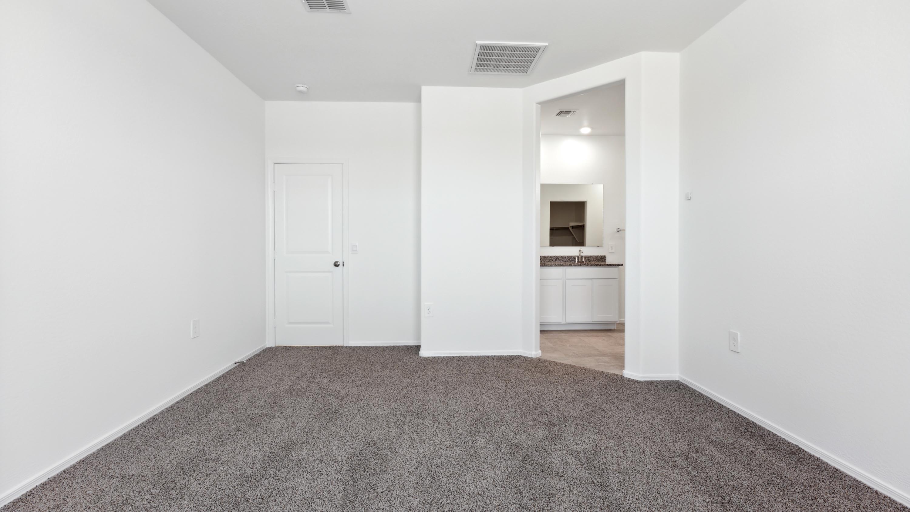 A spacious primary bedroom emphasizing open space and natural lighting.