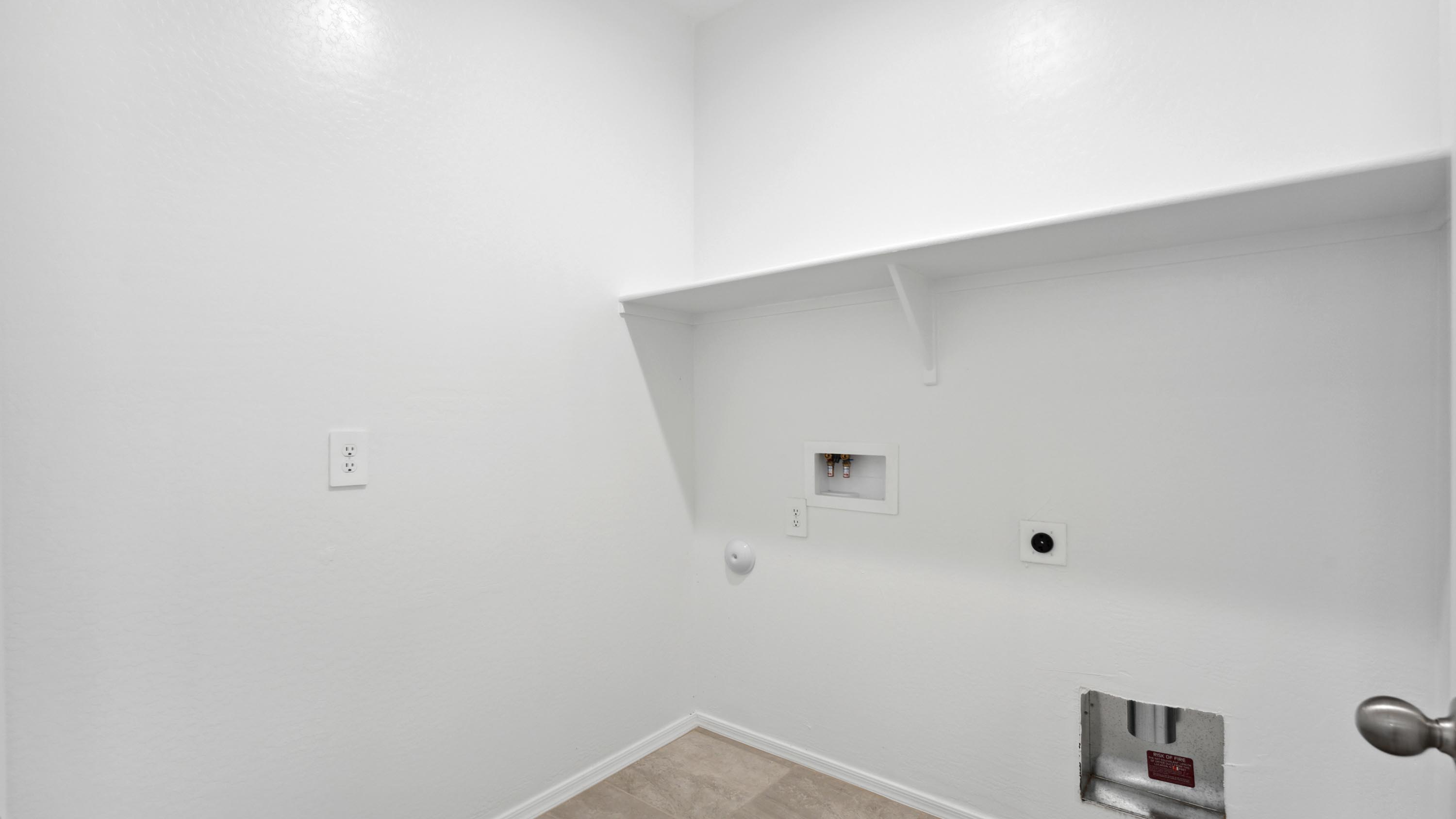 Spacious laundry room with washer and dryer connections and shelving for storage.