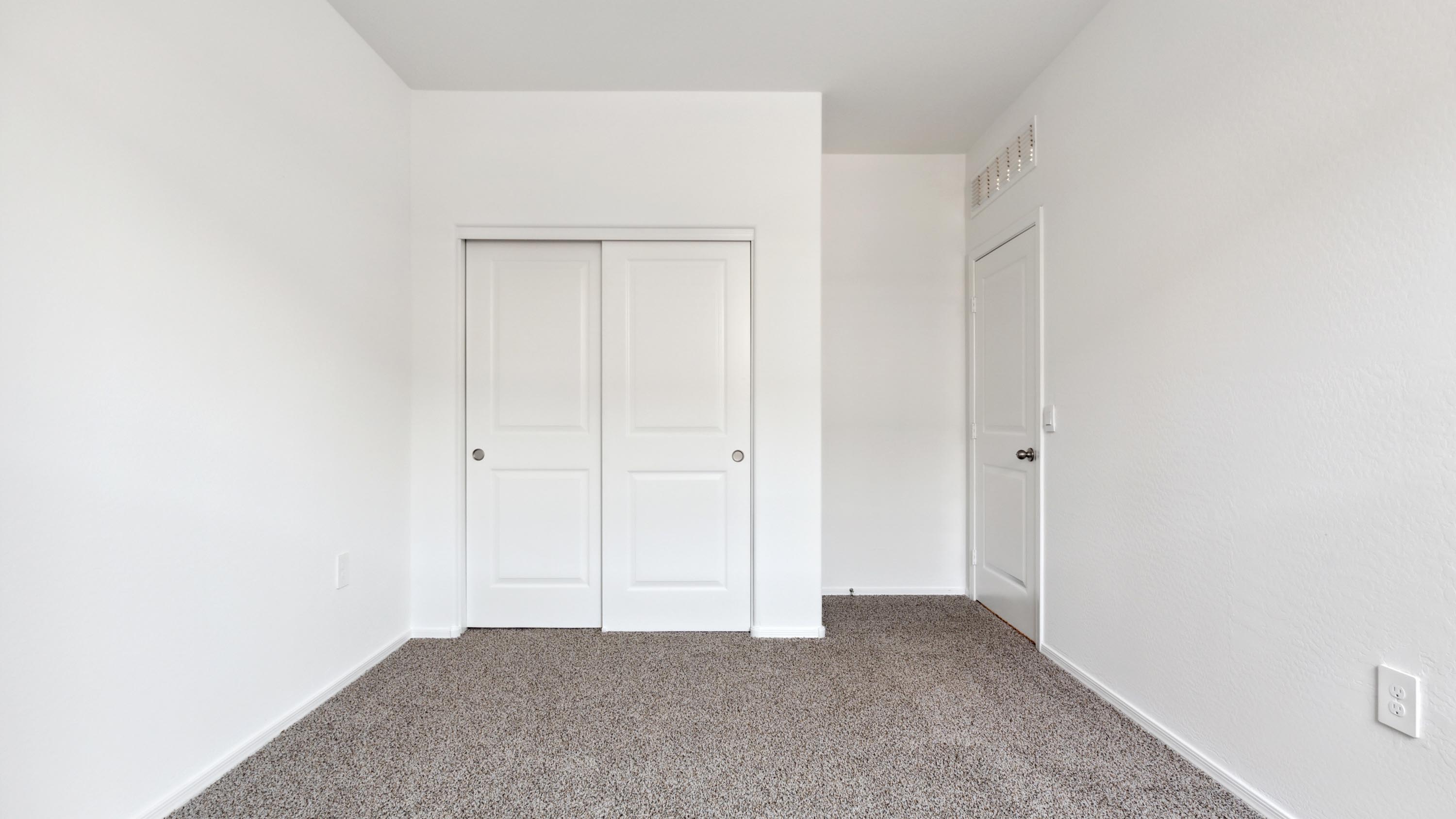 Comfortable guest bedroom featuring neutral-toned walls and a large closet.