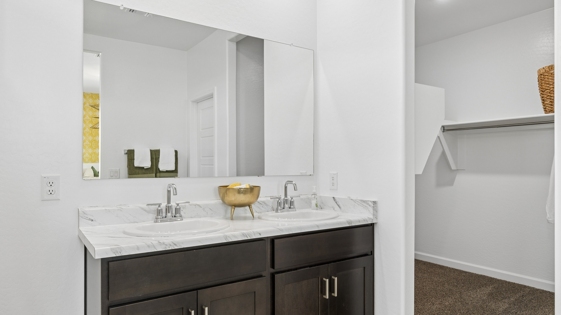 Modern primary bathroom with double vanities, porcelain countertops with a walk-in shower and a walk-in closet.