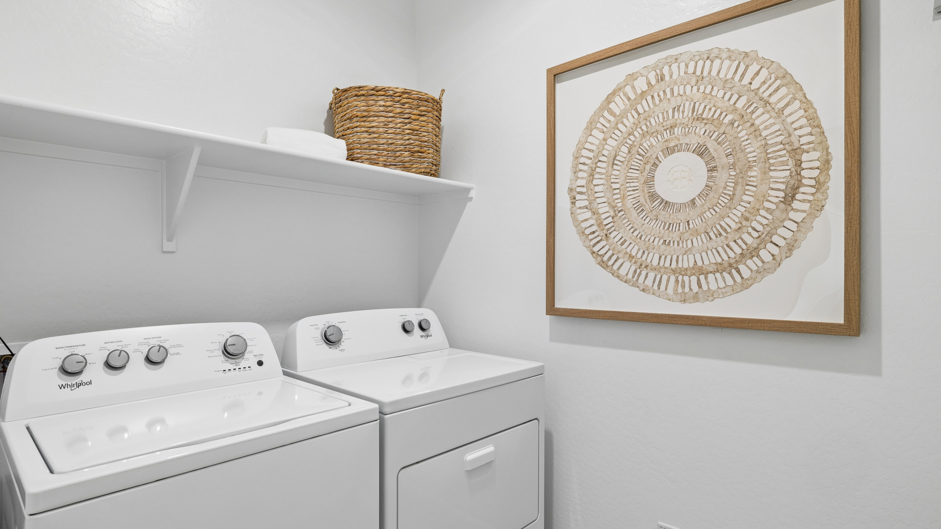 Spacious laundry room with washer and dryer connections and shelving for storage.